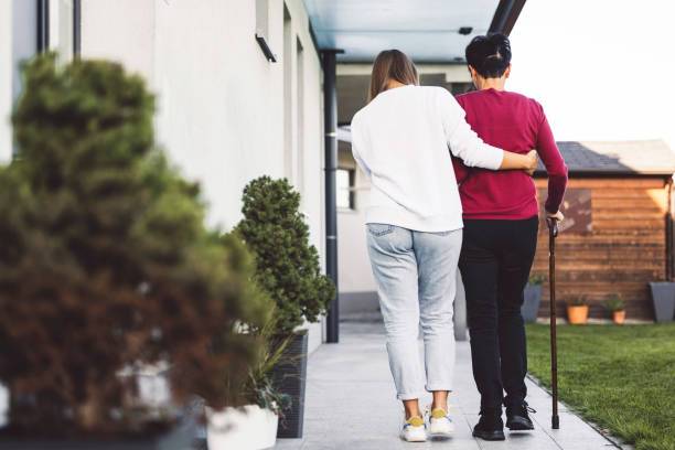 A young female caregiver helping the woman to walk.
